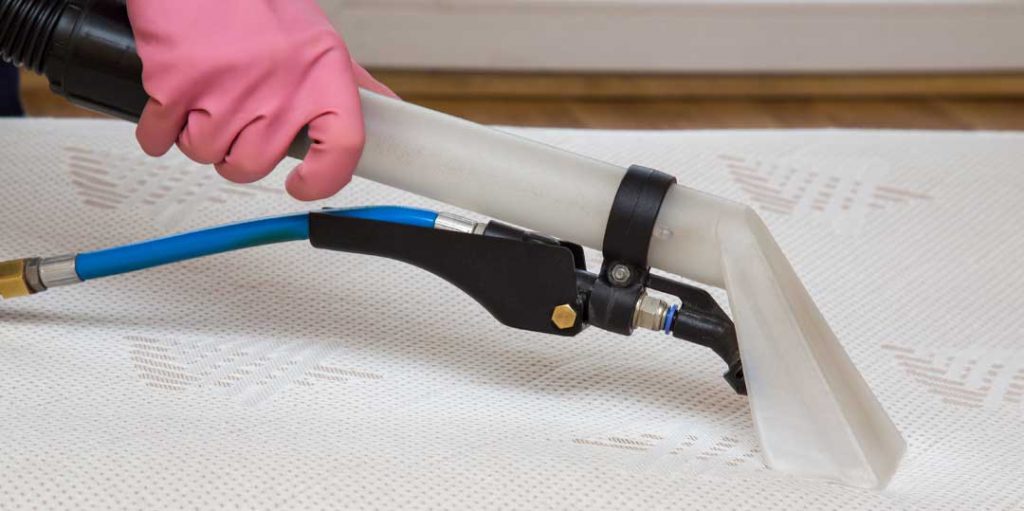 Professional cleaner using equipment to clean a mattress