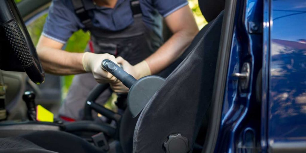 Person cleaning car seats with specialised tools